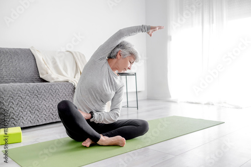 Pleasant 65-Year-Old Woman Does Exercises At Home On A Yoga Mat