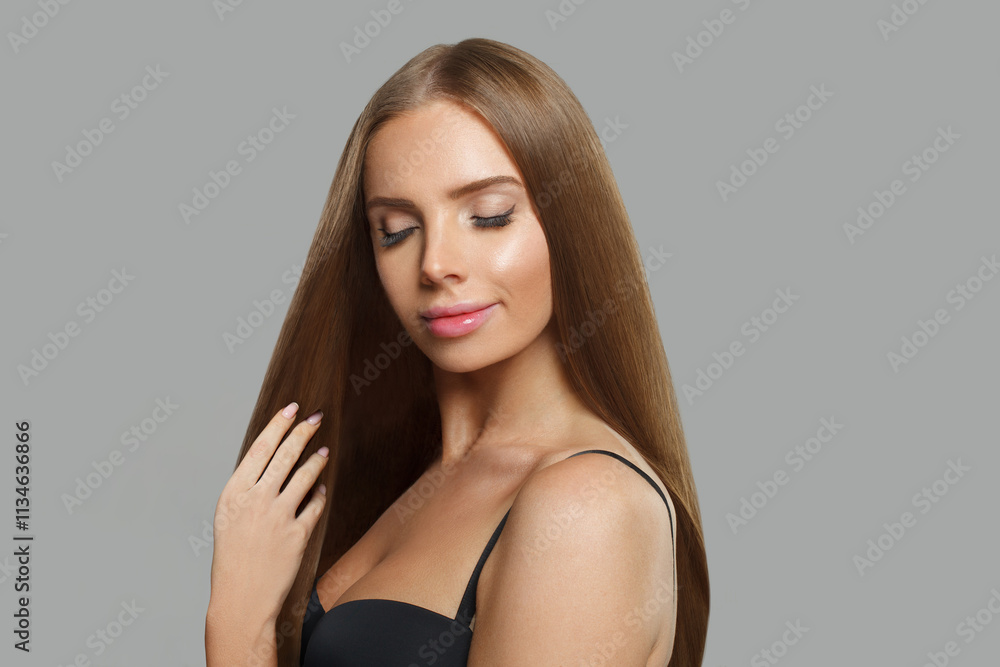 Fototapeta premium Cute young woman model with modern make-up and long straight smooth hairstyle standing on white studio background