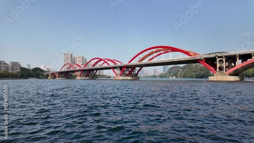 The Wenhui Bridge in Liuzhou, China, features a modern red arched design, over the scenic water of Liujiang River. The modern infrastructure in the Chinese urban city. photo