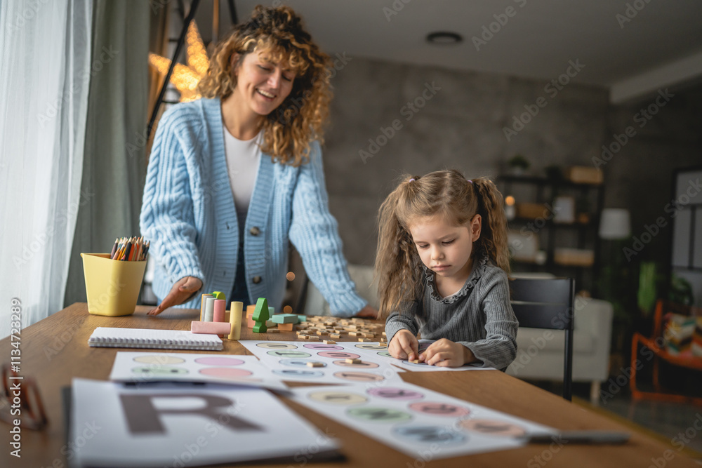 Fototapeta premium little girl practice letters with help speech therapist at home