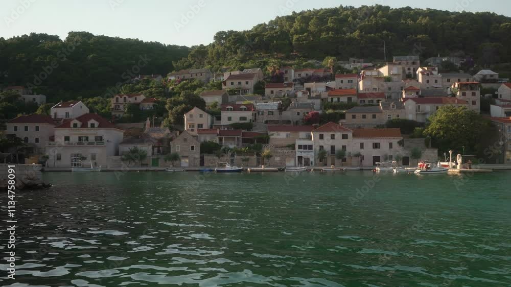The waterfront promenade of a tourist town on a hillside by the sea. Stone houses with tile roofs and charming streets in the port town of Pucisca (Pučišća) on the island of Brac (Brač), Croatia. The waterfront promenade of a tourist town on a hillside by the sea. Stone houses with tile roofs and charming streets in the port town of Pucisca (Pučišća) on the island of Brac (Brač), Croatia.