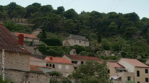 Old stone houses with tiled roofs, located on the hillside. Residential buildings and streets of the tourist town of Pucisca (Pučišća) on the island of Brac (Brač), Croatia. Mediterranean Architecture photo