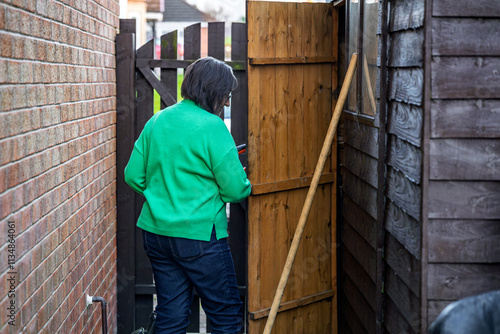 Wallpaper Mural Woman wearing Green Top Storing Weed Whacker Strimmer and Garden Broom in Shed Torontodigital.ca