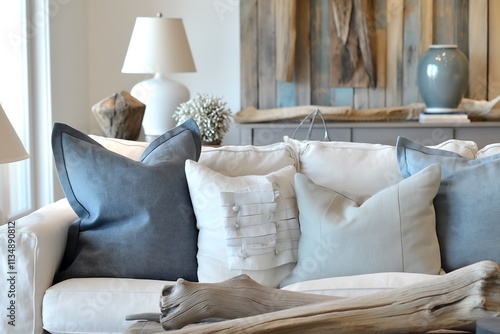 Coastal-inspired living room interior featuring linen slipcovered furniture, driftwood accents, and soft blue throw pillows. photo