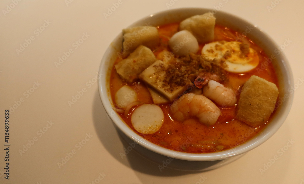 close up of Singaporean Malaysian soup laksa noodles with fishballs, tofu bean curd, prawns, shrimps and fish slice close up of Singaporean Malaysian soup laksa noodles with fishballs, tofu bean curd, prawns, shrimps and fish slice
