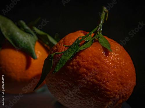 Clemetines with leaves against a black background