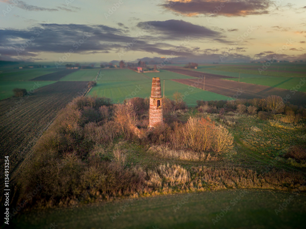 A lonely old chimney in the middle of a field.