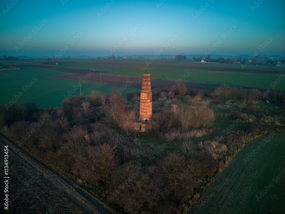 A lonely old chimney in the middle of a field.