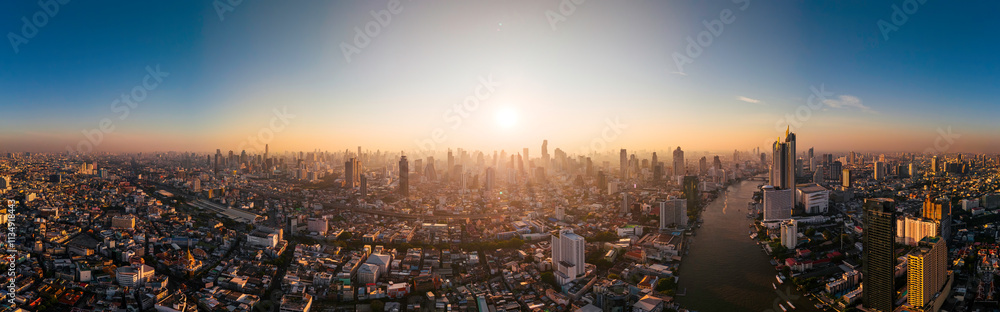 Fototapeta premium Aerial panorama of Bangkok city at amazing sunrise. The first sun rays shine through the tall buildings at dawn