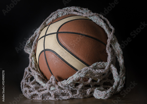 View of Basketball ball inside of Knitting yarn mesh net string bag on dark background, Light and Shadow, use it as your Wallpaper, Poster and Space for text, Selective focus. photo