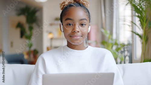 French girl online in living room holding a laptop and earphones