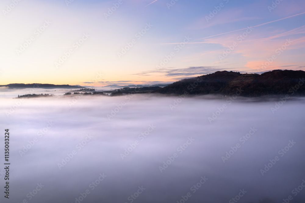 Beautiful atmospheric aerial drone landscape image of cloud inversion in Loughrigg valley in Lake District during Autumn Beautiful atmospheric aerial drone landscape image of cloud inversion in Loughrigg valley in Lake District during Autumn