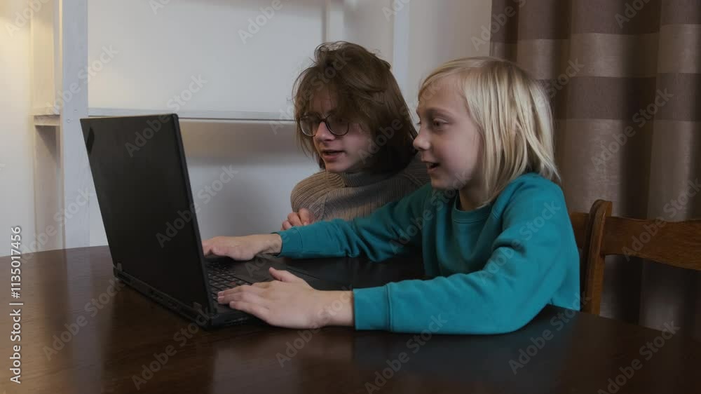 Two young students collaborate on a school project, using a laptop at home in a slow motion setting Two young students collaborate on a school project, using a laptop at home in a slow motion setting