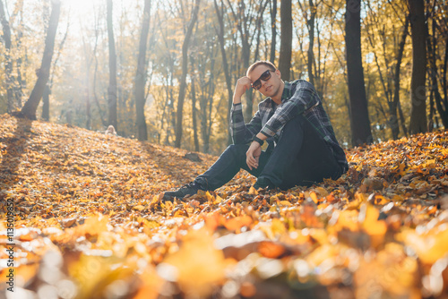 A man sitting on the ground surrounded by leaves. Suitable for outdoor and nature concepts