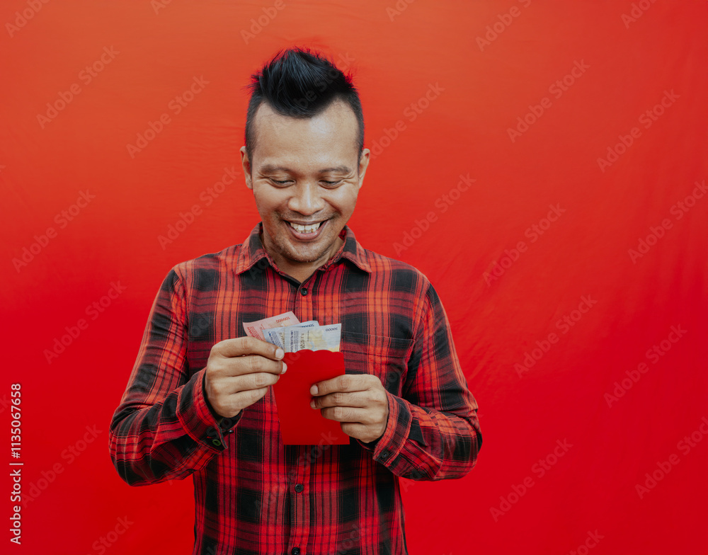 Smiling handsome Asian man holding red envelopes or Ang Pao in studio isolated on red background for Chinese new year concepts. Smiling handsome Asian man holding red envelopes or Ang Pao in studio isolated on red background for Chinese new year concepts.