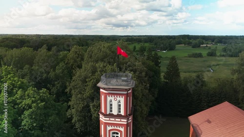 Drone footage over Alanta Manor in Alanta, Lithuania with dense forest trees and cloudy sky photo