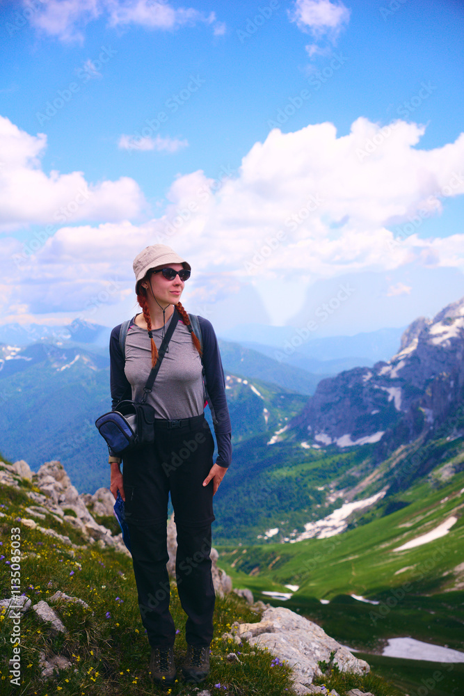 a young girl with a backpack stands and smiles against the background of mountains and nature a young girl with a backpack stands and smiles against the background of mountains and nature