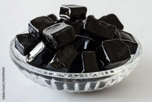  A small bowl of Finnish salmiakki licorice candies, black and glossy.