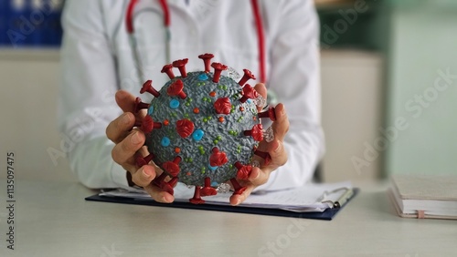 The doctor holds a model of the coronavirus, the concept of mutation covid-19, close-up, blurry photo