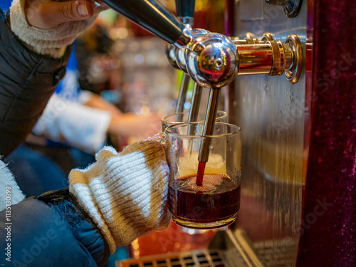 woman in the bar pours mulled wine into the glass. close - up.