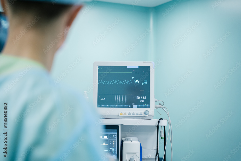 A skilled surgeon closely watches the monitor showing critical patient data in a sterile environment.