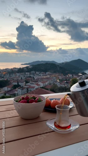 VERTICAL Romantic tea scene, fresh fruits, terrace with seaside town view
