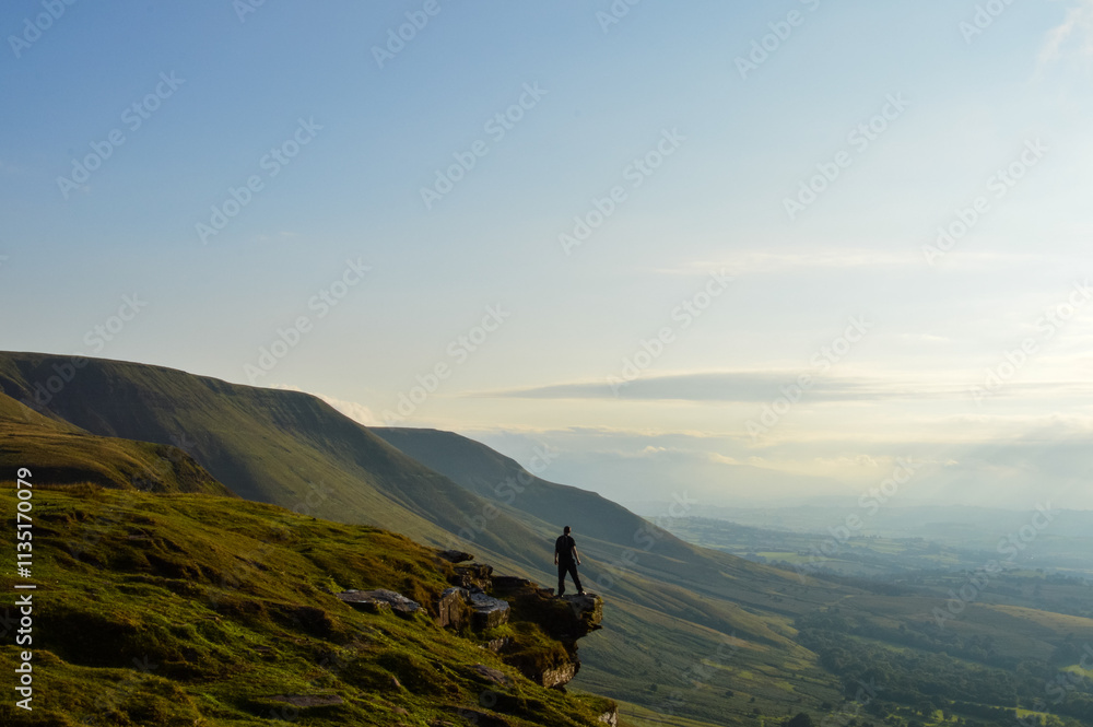 A man standing back to camera on an escarpment in the mountains. Brecon Beacons Wales, UK A man standing back to camera on an escarpment in the mountains. Brecon Beacons Wales, UK