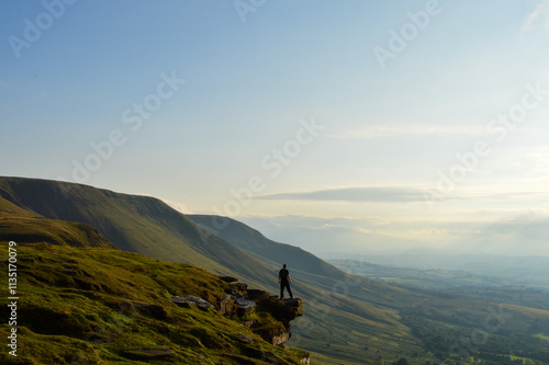A man standing back to camera on an escarpment in the mountains. Brecon Beacons Wales, UK
