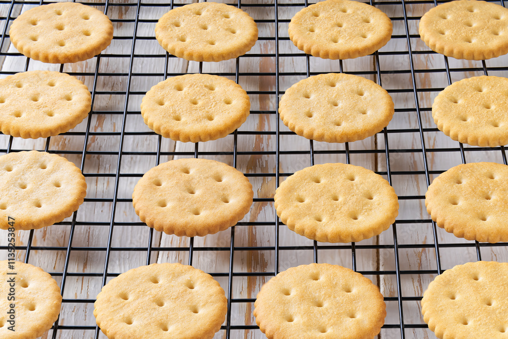 Wheat round crackers in a black wire rack on a white table, close up. Wheat round crackers in a black wire rack on a white table, close up.