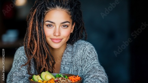 Healthy bowl filled with colorful vegetables and grains held by a person indoors