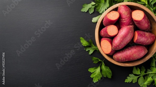 Fresh sweet potatoes arranged in a bowl with green herbs on a dark surface