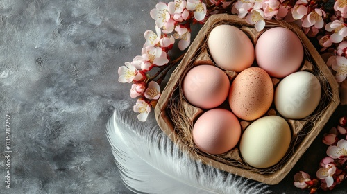 Colorful Easter eggs arranged with pink blossoms on a pastel pink background