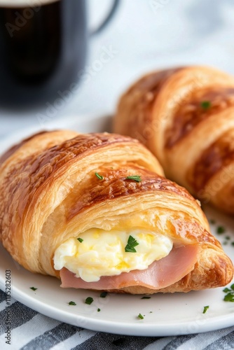 Delicious ham and cheese croissant with egg served on a plate with coffee in ...