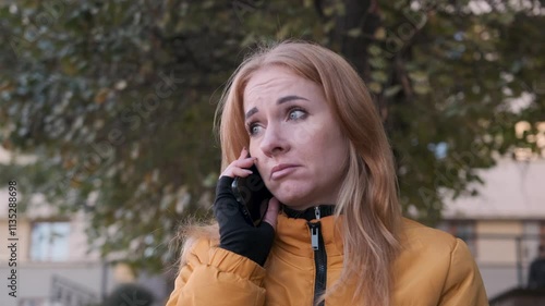 Woman receiving bad news on the phone displays sadness with tears in her eyes, showcasing deep emotions in slow motion