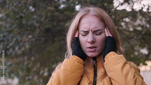 Young woman suffering from a headache, holding her head in slow motion, conveys feelings of pain and distress