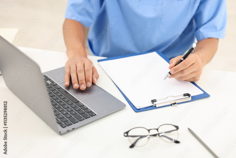 Medical student taking notes while studying with laptop at table indoors, closeup Medical student taking notes while studying with laptop at table indoors, closeup