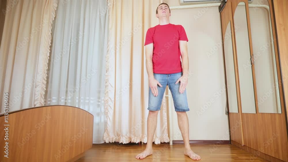 Man doing squats and exercising in bedroom at home Man doing squats and exercising in bedroom at home