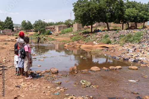 Group of children on their way to school in an African village wondering how to cross a flooded area in their village after heavy rainstorms, concept of environmental devastation due to climate change photo