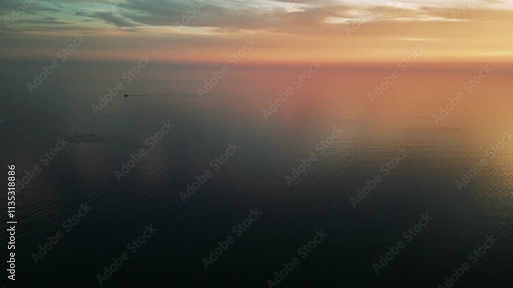 Small boat is sailing on a calm mediterranean sea, leaving a wake behind it. The sky is a beautiful sunset with orange and pink hues Small boat is sailing on a calm mediterranean sea, leaving a wake behind it. The sky is a beautiful sunset with orange and pink hues