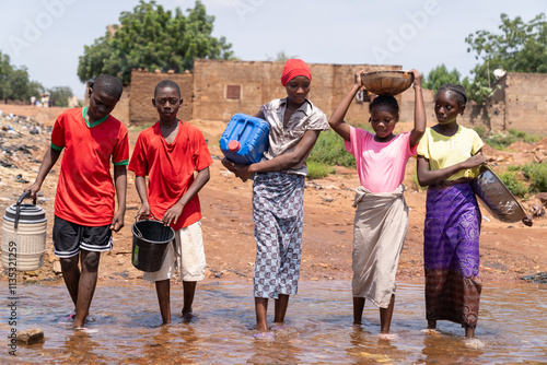 African children cross a flooded area on their way to the public water tap, symbolizing the contradiction between extreme flooding and drinking water shortages affecting third world countries