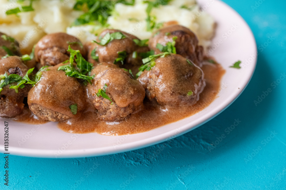 Swedish Meatballs with Gravy Sauce on a plate with mashed potatoes on a wooden background Swedish Meatballs with Gravy Sauce on a plate with mashed potatoes on a wooden background