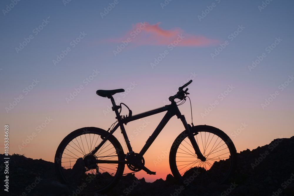 The silhouette of a bike on the sunset sky background The silhouette of a bike on the sunset sky background
