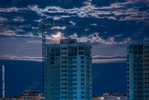 Wallpaper Mural An urban cityscape at twilight, featuring three tall apartment buildings with reflective windows A construction crane is visible in the foreground, while the sky is filled with gradating clouds and Torontodigital.ca