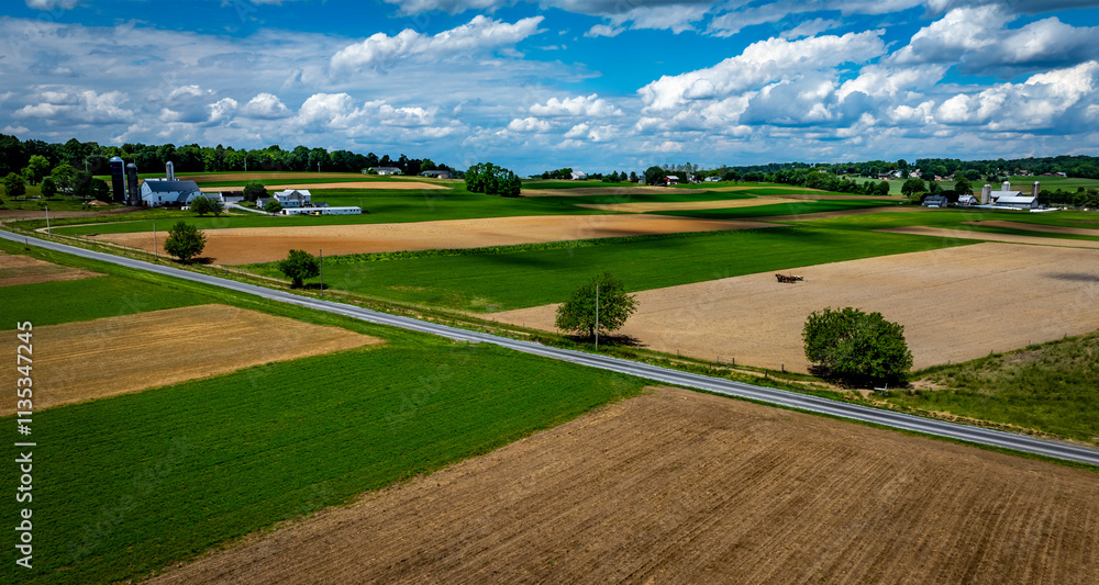 Vast agricultural fields dominate the landscape, showcasing a mix of green crops and brown earth. Vast agricultural fields dominate the landscape, showcasing a mix of green crops and brown earth.