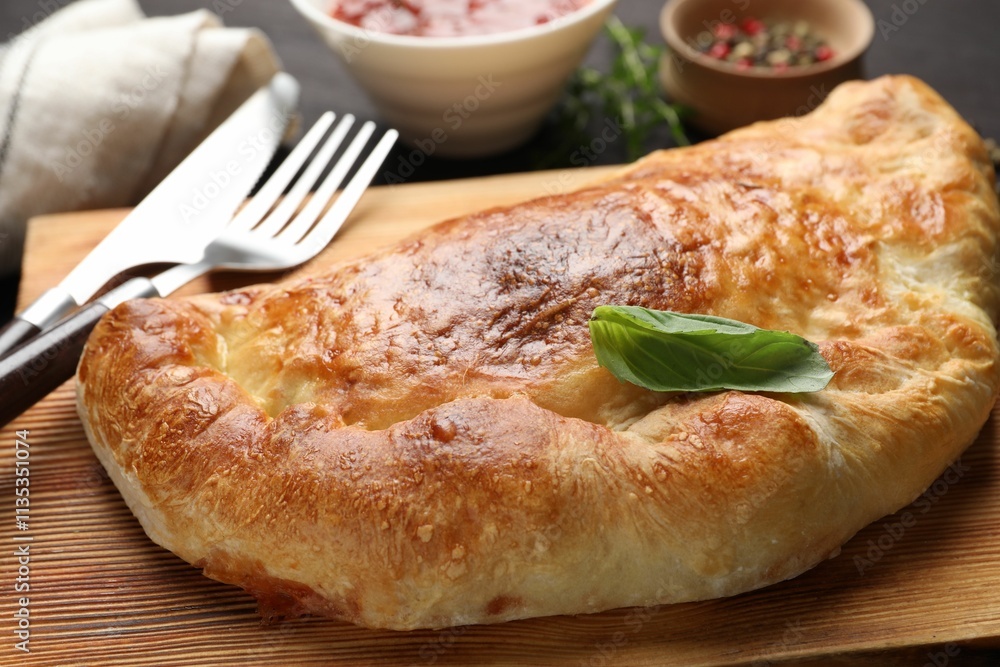 Delicious fresh calzone pizza served on wooden table, closeup Delicious fresh calzone pizza served on wooden table, closeup