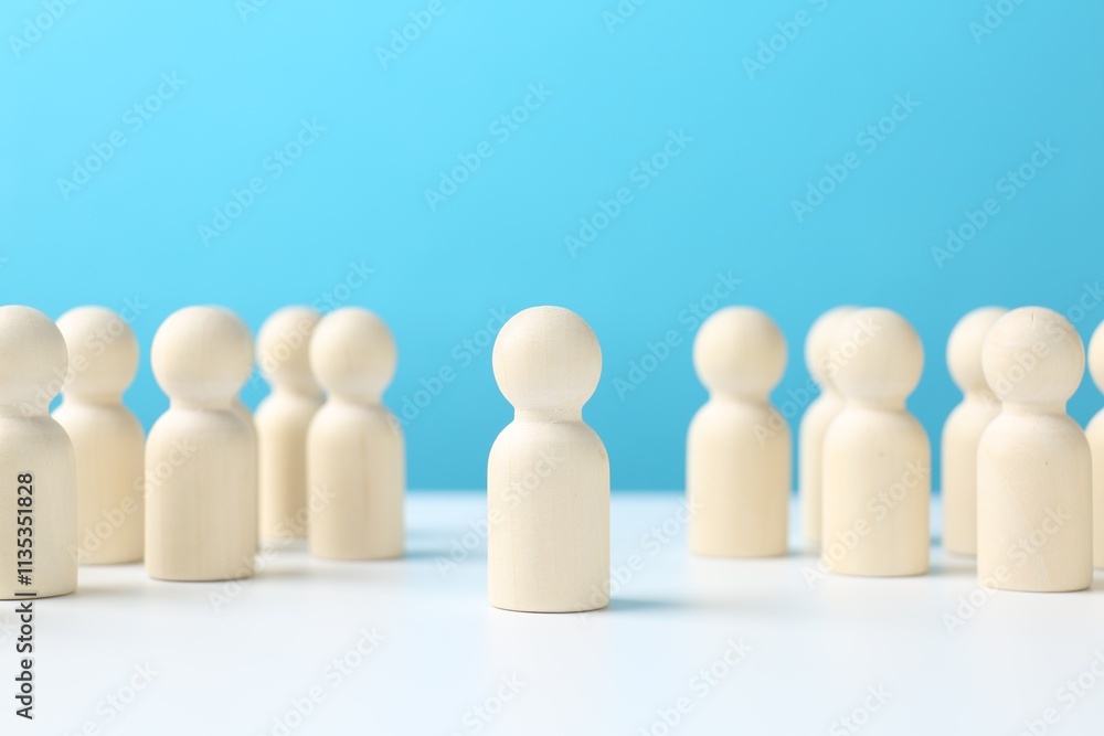 One human figure standing out among others on white table against light blue background. Competition concept One human figure standing out among others on white table against light blue background. Competition concept