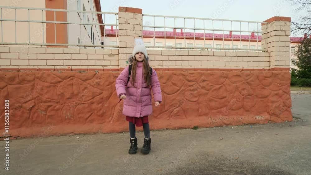 Little girl goes school with backpack winter, girl with backpack walks through school yard. Little girl goes school with backpack winter, girl with backpack walks through school yard.