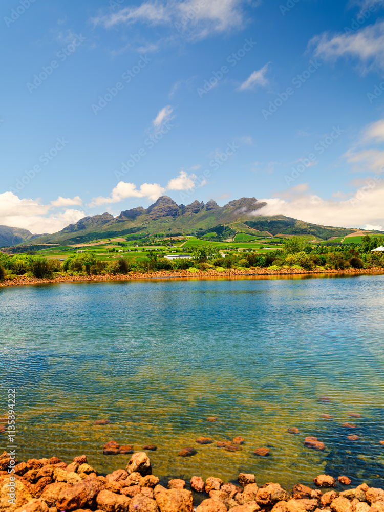 Vertical view of Helderberg Mountain with vineyards on the slopes and a crystal-clear water dam, Somerset West, South Africa