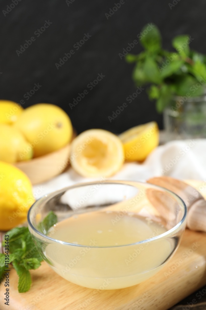 Fresh lemon juice in bowl and fruits on wooden table, closeup Fresh lemon juice in bowl and fruits on wooden table, closeup