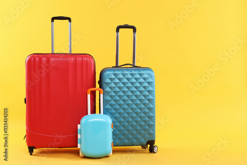 Different packed suitcases on yellow background. Travel luggage